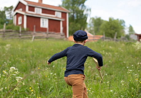 barn springer i naturen i småland med röda hus