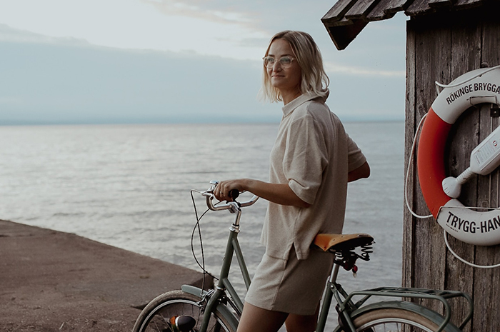 Kvinna med cykel på brygga vid vatten