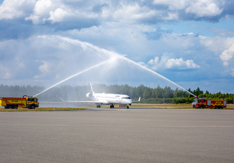 Flygplan hälsas välkommet av en vattenkaskad från tankbilar.